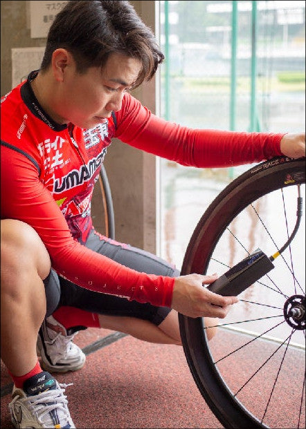 競輪選手の松岡辰泰さんが、レーサーのタイヤに PANP RIDE をつないでいる