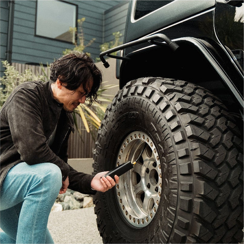 車のタイヤにPANP RIDEをつないで空気を入れる男性