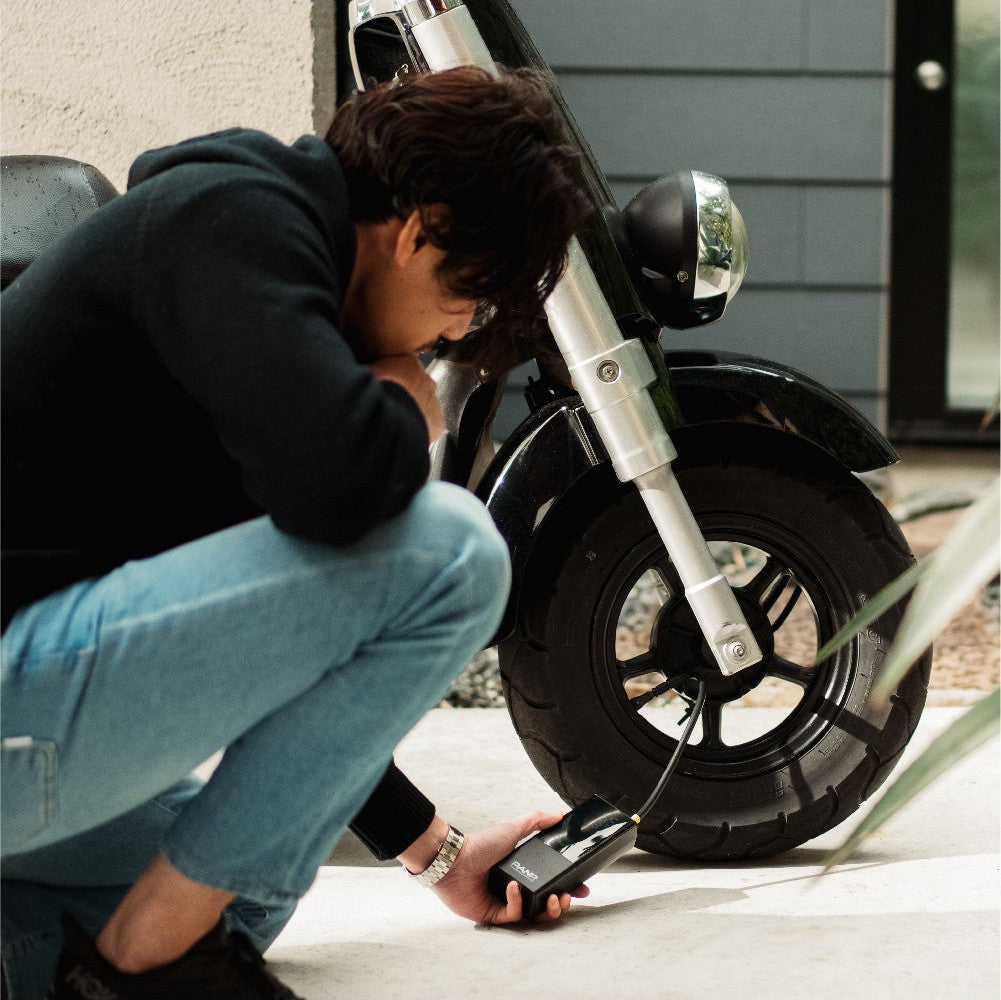 バイクのタイヤにPANP RIDEをつないで空気を入れる男性