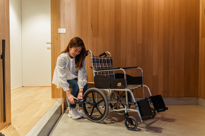 玄関で、車いすのタイヤに PANP RIDE をつないでいるところ