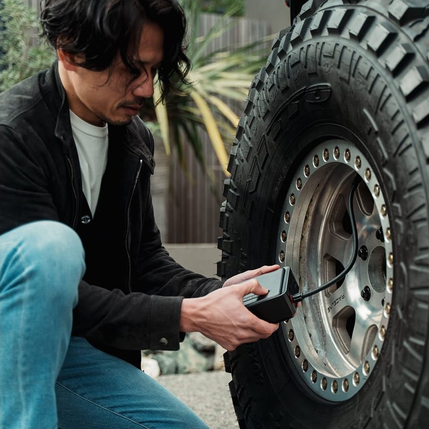 車のタイヤに PANP RIDE PRO をつないで空気圧をみる男性